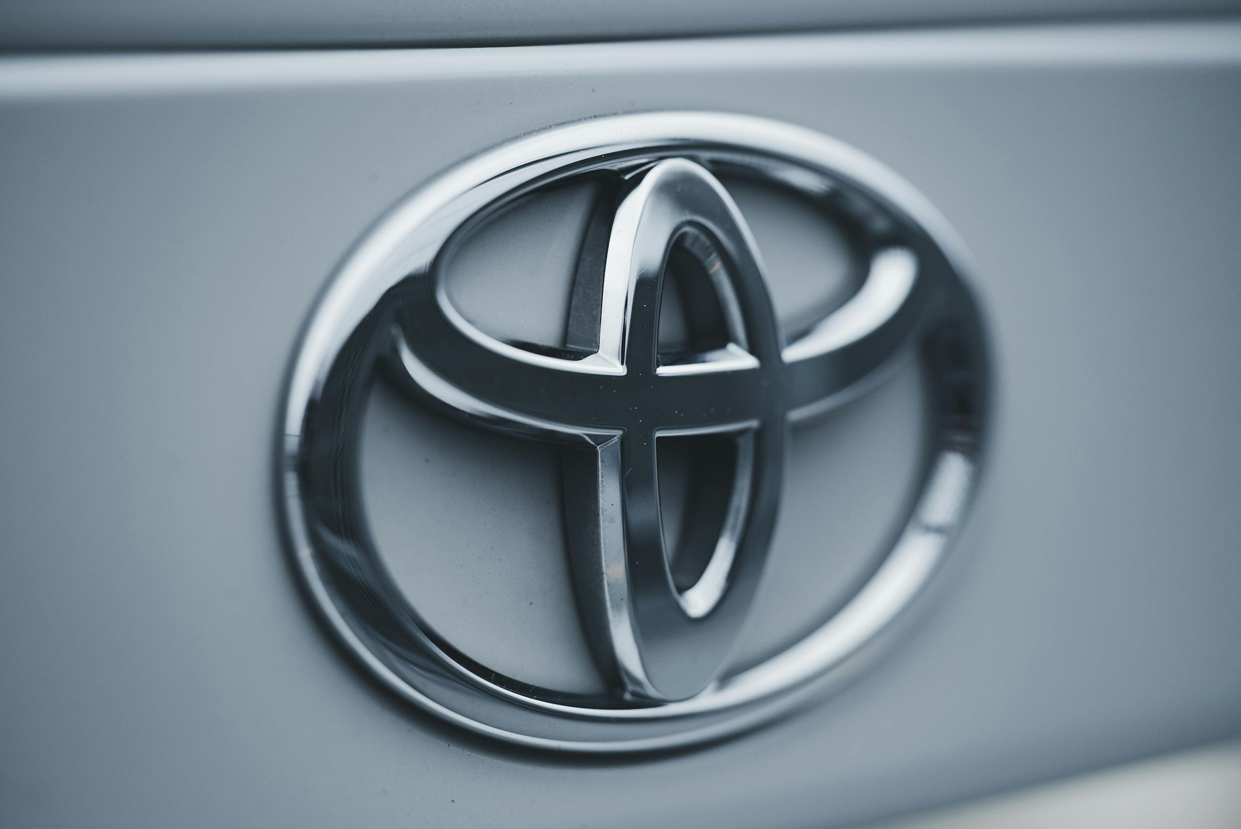 Detailed image of a shiny silver Toyota emblem on a vehicle's surface.